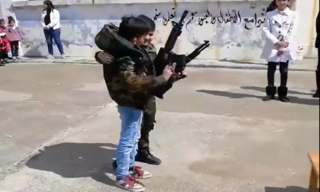 مدرسة سورية تثير الجدل باستخدامها طفلين لتشجيعهما على حمل السلاح "فيديو" alarabtrend.com